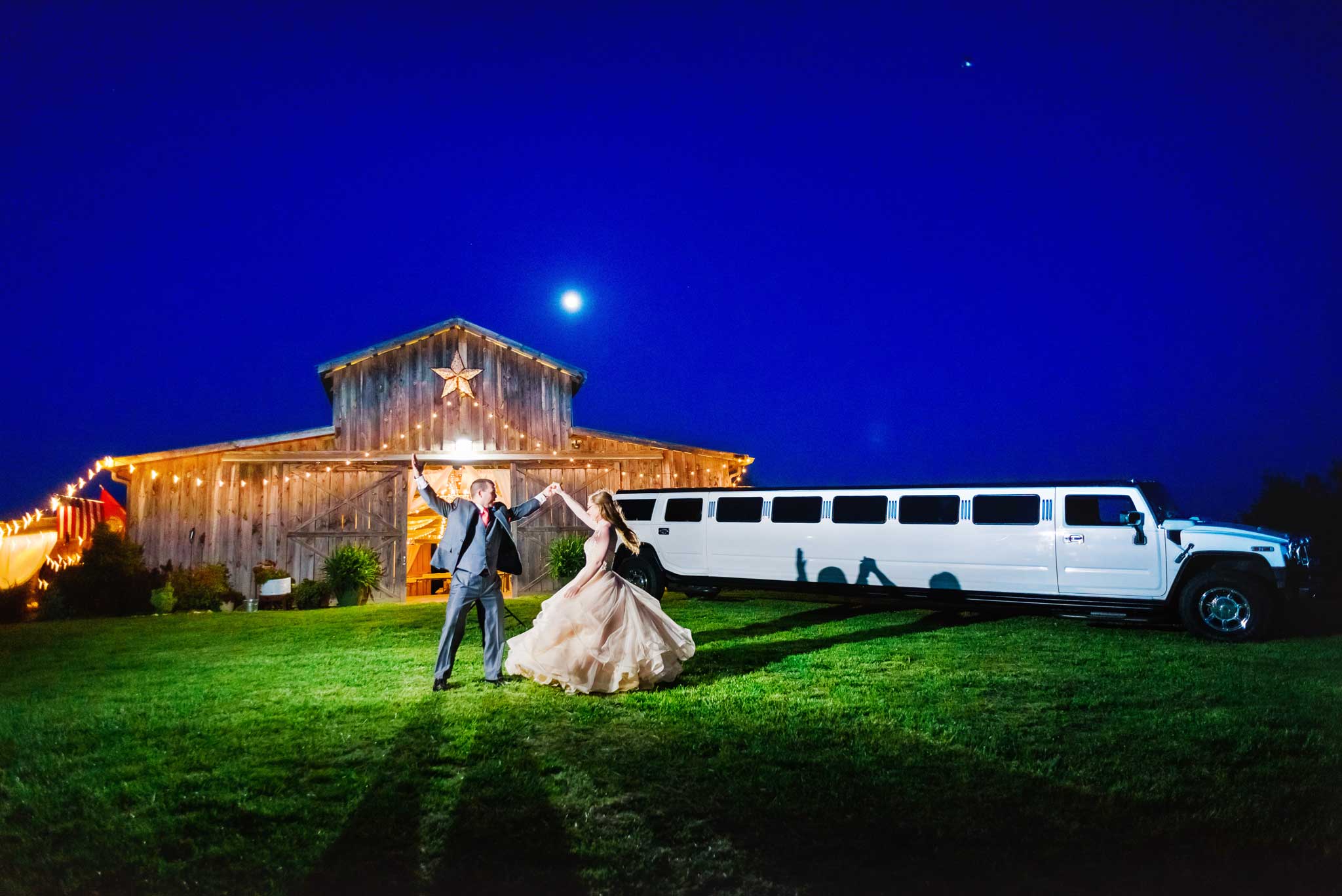 Nighttime dancing in front of the barnat drewia hill with a white hummer limo and bride and groom