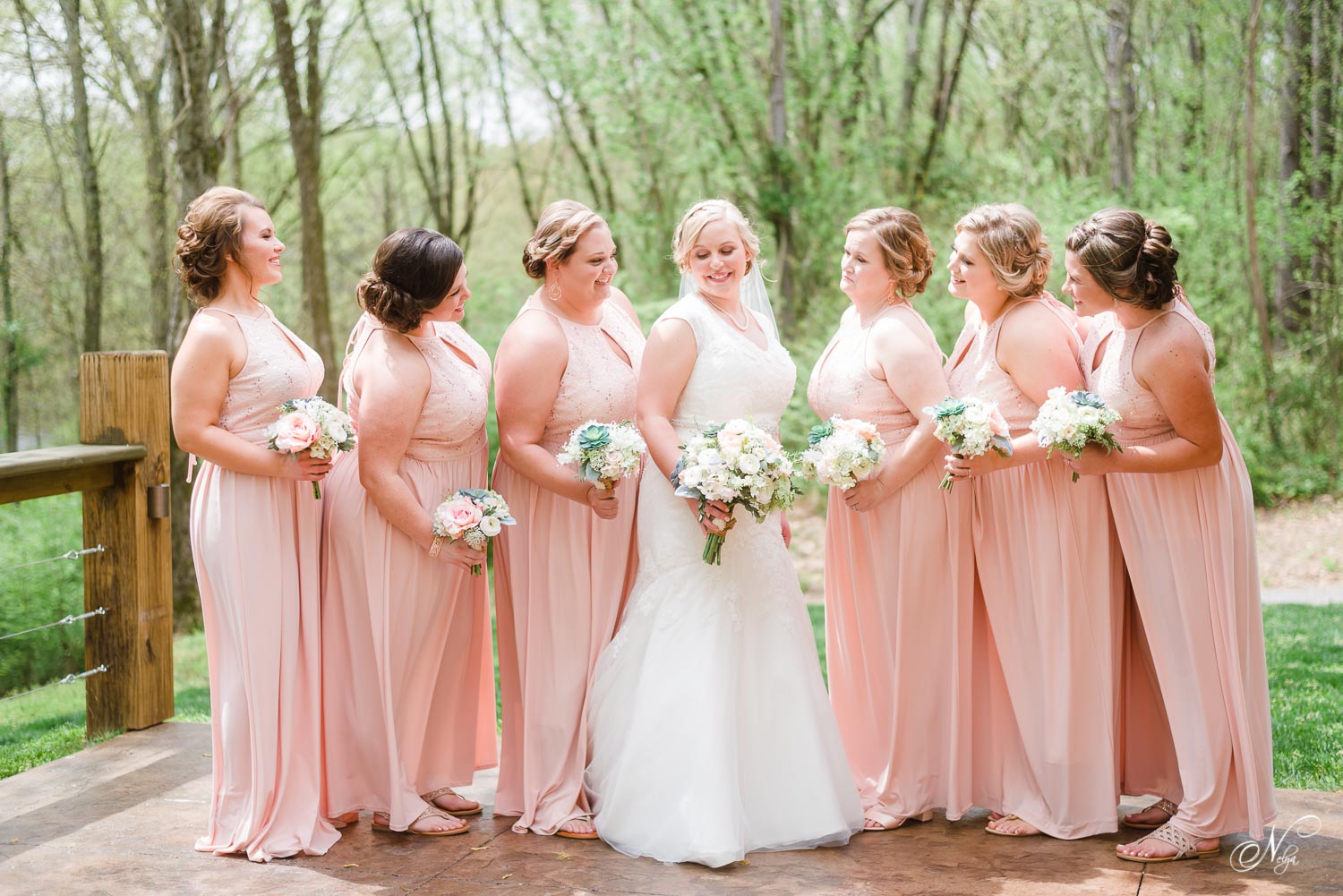bridesmaids in coral long dresses on the patio over looking the river at Hiwassee river weddings