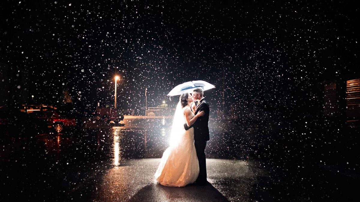 military couple under umbrella in the rain on the night of their wedding in Tennessee