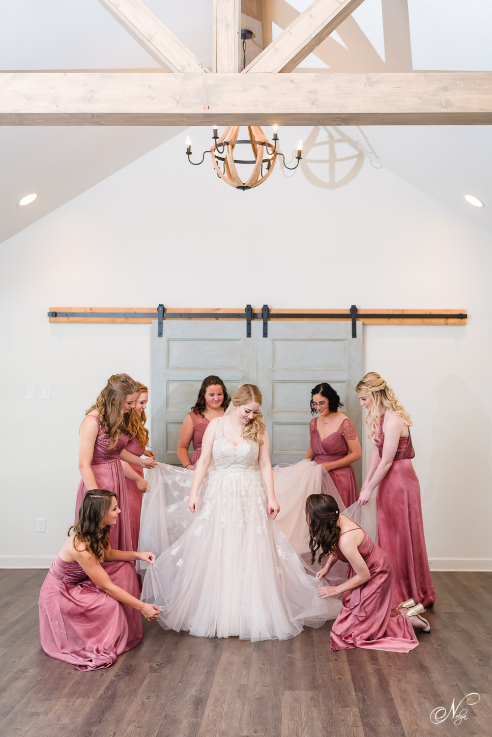 seven bridesmaids in maroon dresses helping bride get in her wedding dress in Chattanooga TN