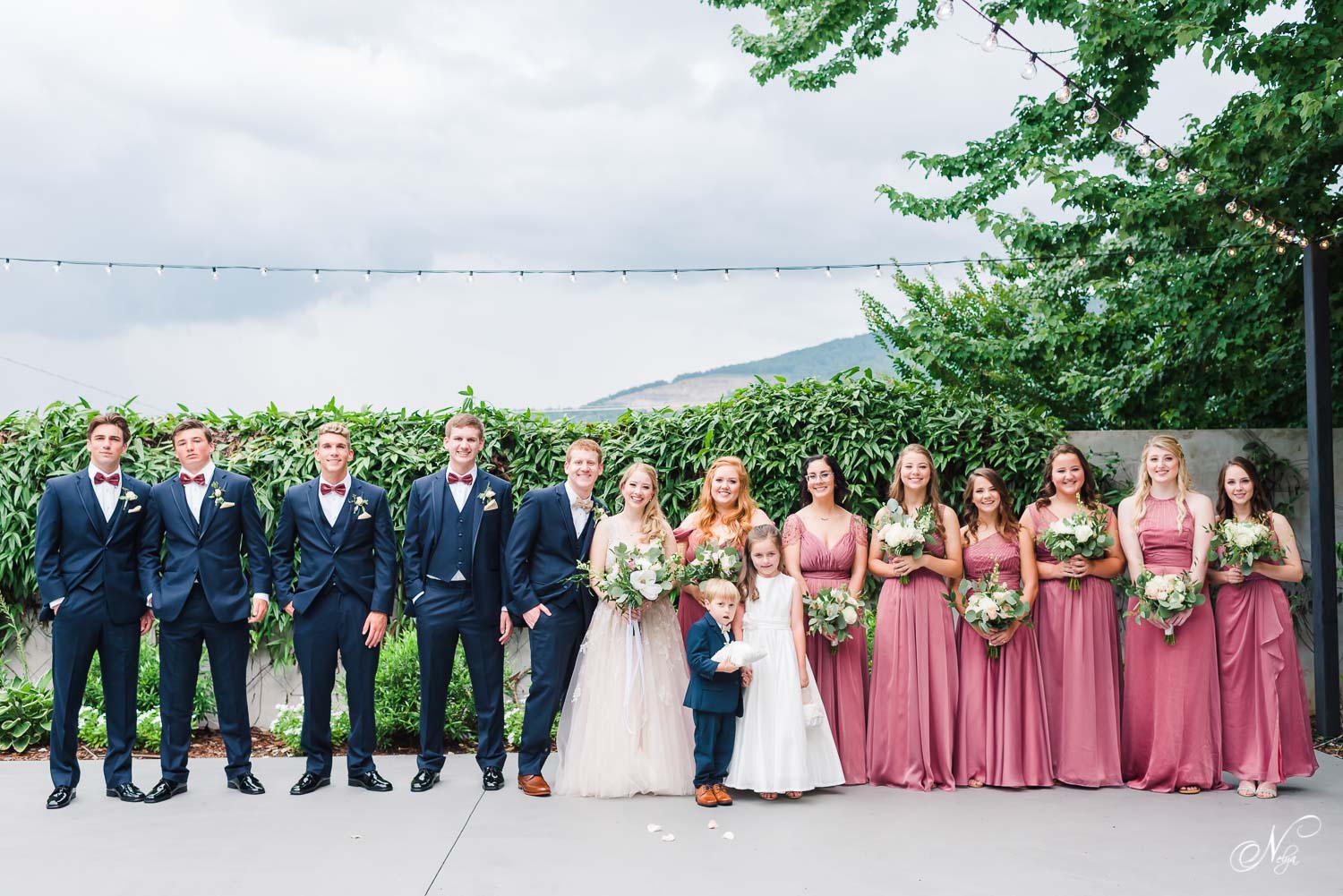 wedding party in navy suits and dusty wine dresses outside on a cluody day at the upper patio area at The Venue Chattnaooga in Chattanooga TN