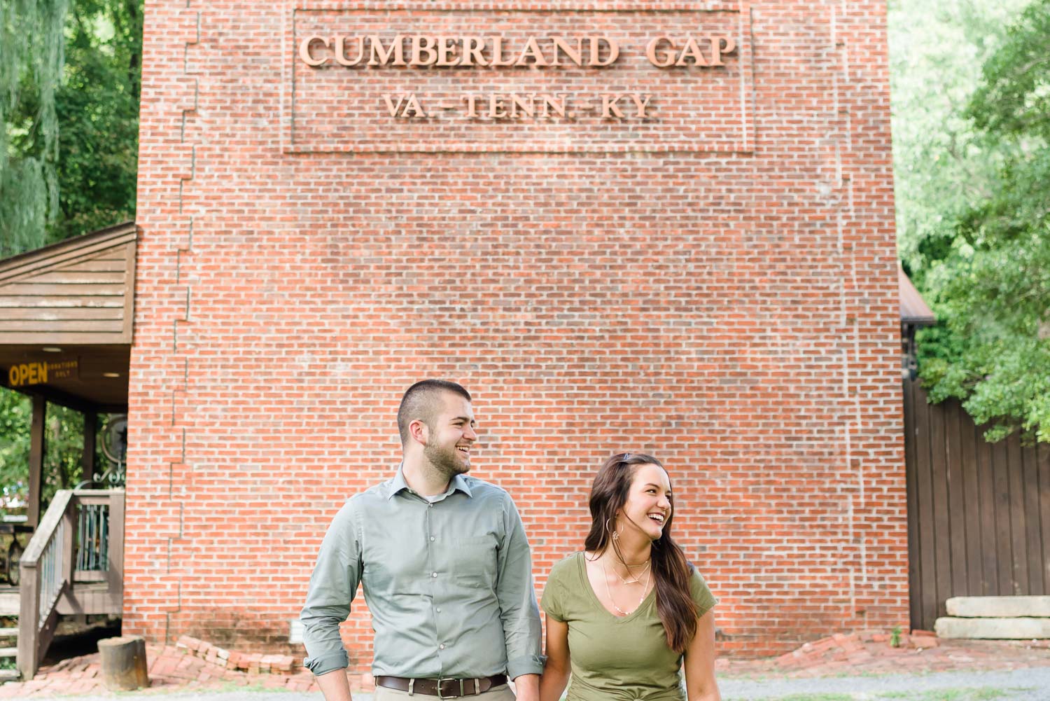 laughing couple outside in front of brick building of the Little Congress Bicycle museum in Cumberland Gap TN