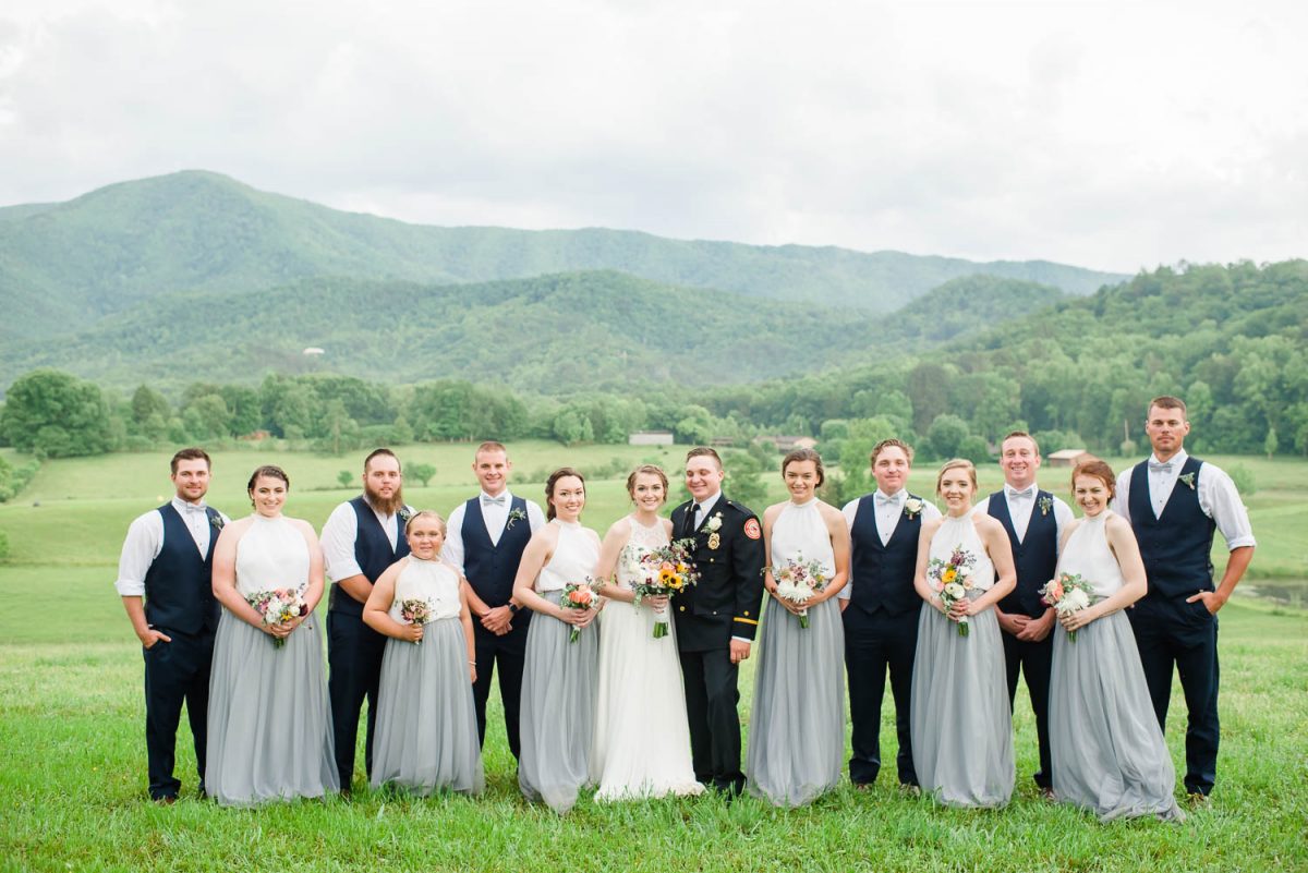 bridesmaids in long gray tulle skirts with groomsmen in dark blue suits in front of mountains in Tennessee
